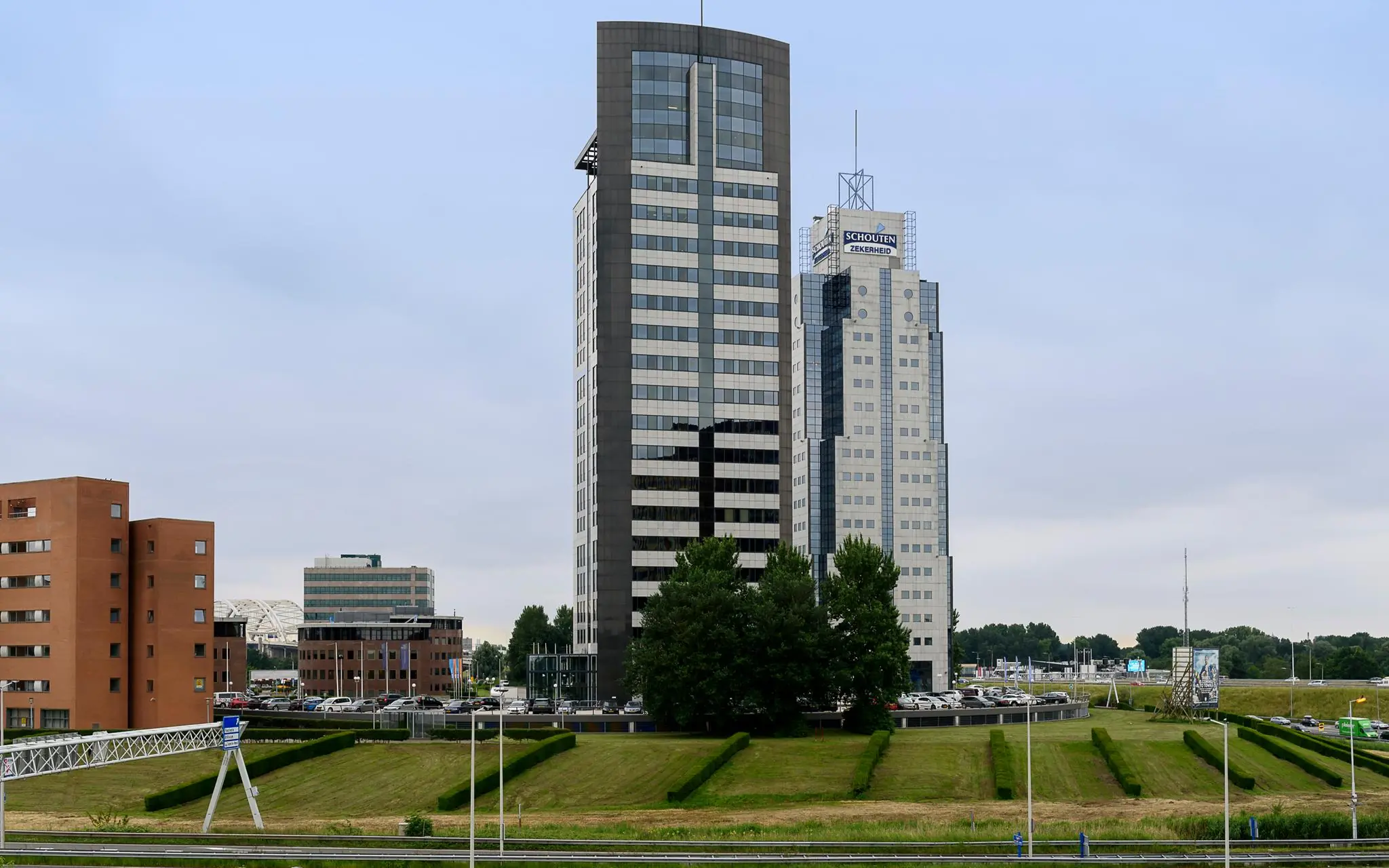 Twee moderne kantoorgebouwen aan het Rivium Quadrant in Capelle aan den IJssel, naast de snelweg en omringd door groenstroken.